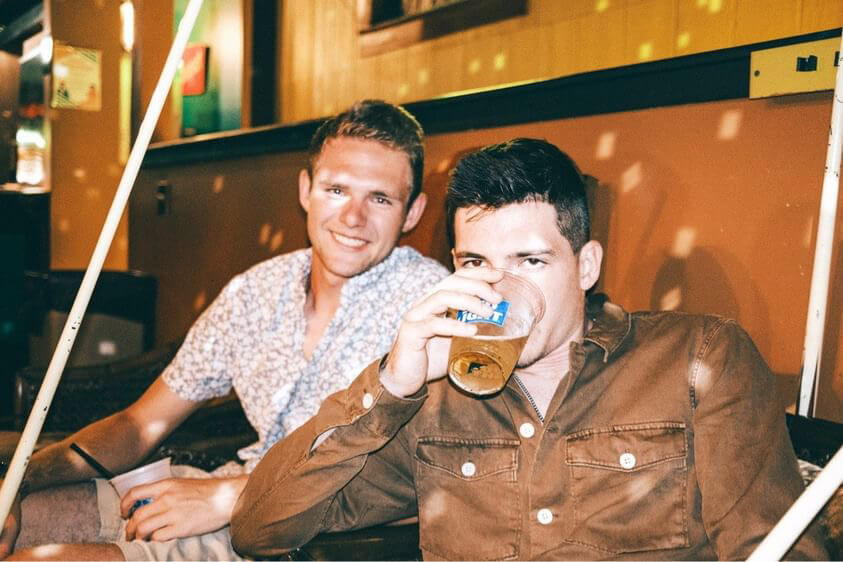 Two friends drinking beer at Louise's — the best college bar in Lawrence KS