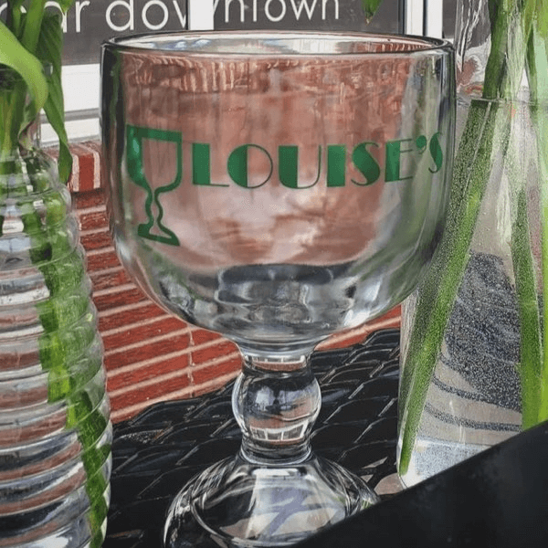 Louise's branded schooner glass on the patio — iconic Lawrence bar