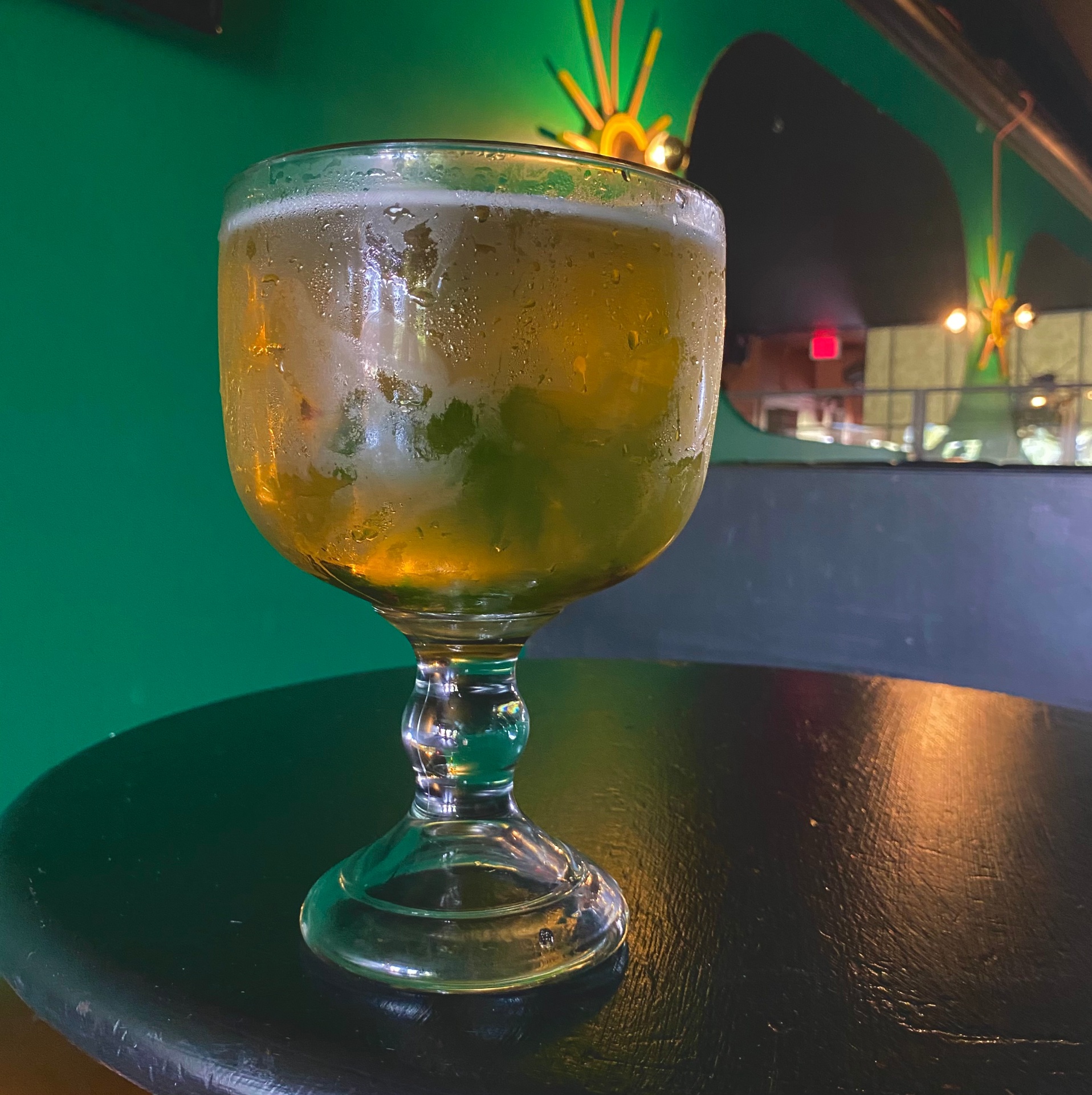 Cold schooner of beer with green neon glow at Louise's — dive bars Lawrence KS